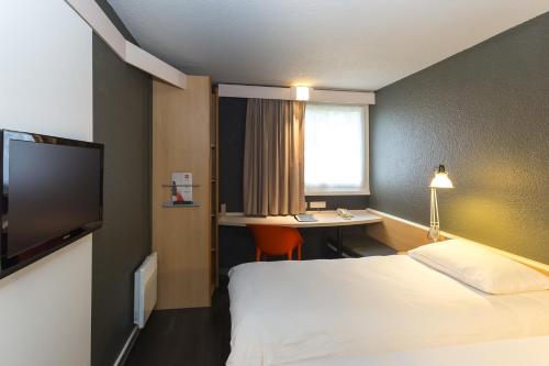 a hotel room with a bed and a desk at ibis Lorient Centre Hôtelier in Caudan