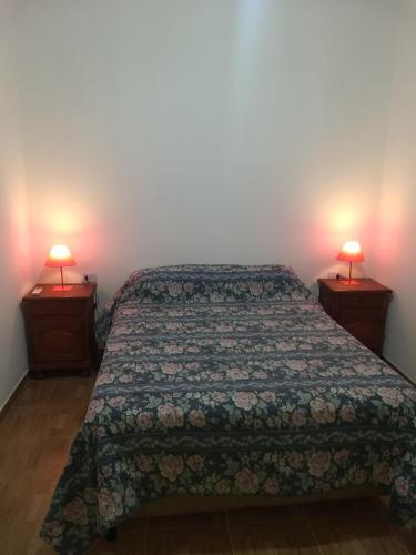 1 dormitorio con 1 cama y 2 lámparas en 2 mesas en Cabaña La Angostura en Fiambala