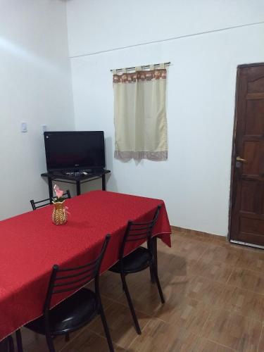 Habitación con mesa roja con sillas y TV. en Cabaña La Angostura en Fiambala