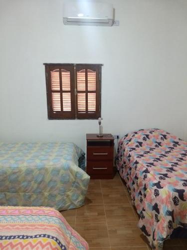 a room with two beds and a dresser and a window at Cabaña La Angostura in Fiambala