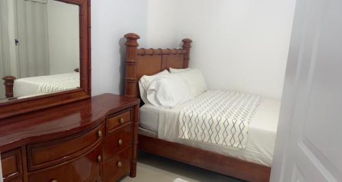 Schlafzimmer mit einem Bett, einer Kommode und einem Spiegel in der Unterkunft Casa acogedora y familiar in Constanza