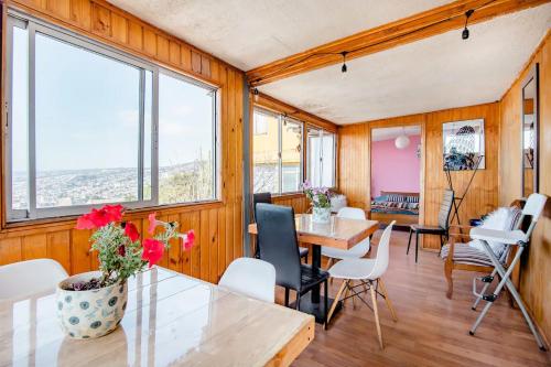 a room with a table and chairs and windows at Casa Altavista in Valparaíso