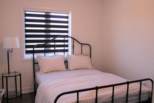 a bedroom with a bed with two pillows and a window at New Town House Barrie South in Barrie