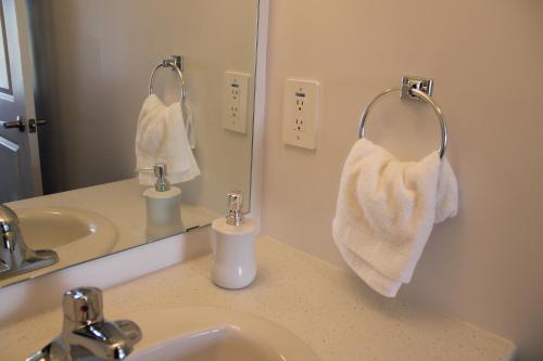 ein Badezimmer mit einem Waschbecken, einem Spiegel und Handtüchern in der Unterkunft New Town House Barrie South in Barrie