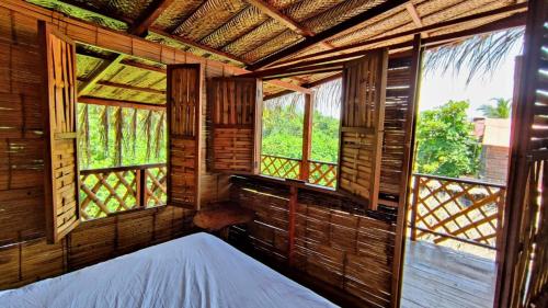 um quarto com uma cama num quarto com janelas em Hostal halaliku em Santa Marta