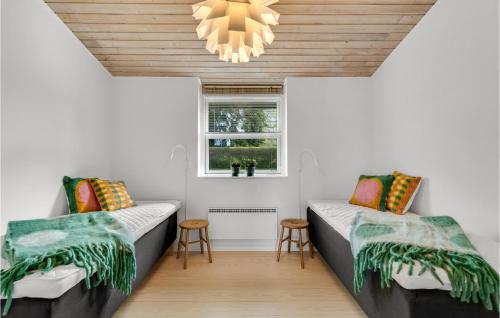 two beds in a room with a window and a chandelier at Awesome Home In lsted With Wifi in Ølsted