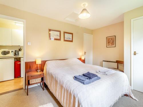 a bedroom with a white bed and a kitchen at Water Hall Cottage in Chelsworth