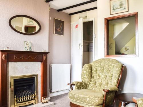 uma sala de estar com uma cadeira e um espelho em Cosy Cottage em Allonby