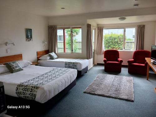 une chambre d'hôtel avec deux lits et deux chaises dans l'établissement Anatoki Lodge Motel, à Takaka