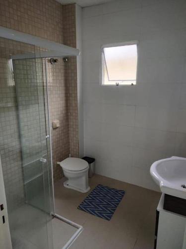 a bathroom with a shower and a toilet and a sink at Casa bem localizada in Guarujá