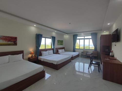 a hotel room with two beds and a desk at Hoàng Anh Côn Đảo Hotel in Con Dao