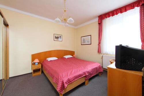 a bedroom with a bed and a flat screen tv at Hotel Blaha Lujza in Balatonfüred