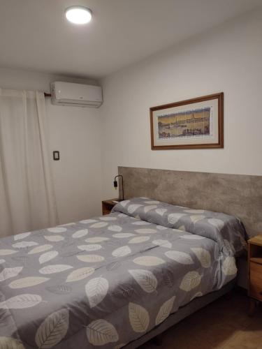 a bedroom with a bed with a gray and white bedspread at Departamento amoblado Rio Cuarto in Río Cuarto