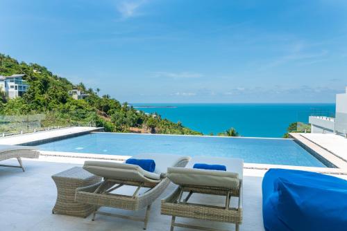 a pool with chairs and a view of the ocean at BLUE BUTTERFLY Luxury Pool Villa Koh Samui 5 Bedrooms in Koh Samui 