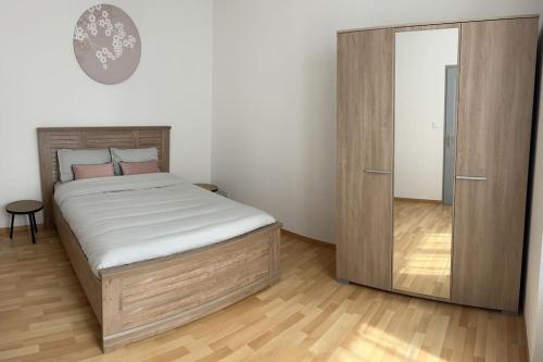 ein Schlafzimmer mit einem großen Bett und einem Holzschrank in der Unterkunft Faubourg de Montbé in Montbéliard