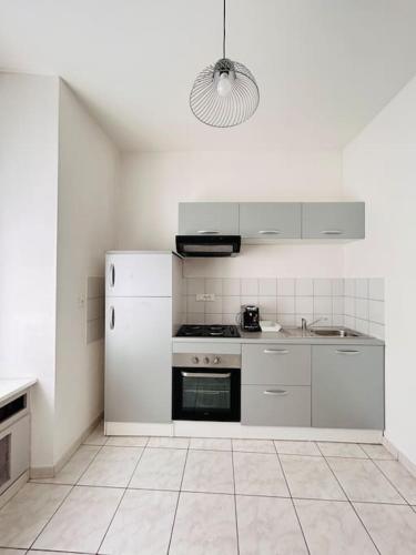 une cuisine blanche avec une cuisinière et un évier dans l'établissement Appartement 1 chambre rue Faubourg de Besançon, à Montbéliard