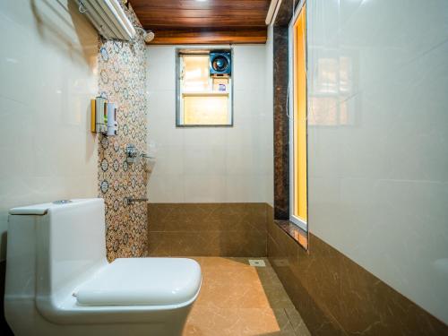 a bathroom with a toilet and a shower with a window at Red Button Resort in Mahabaleshwar