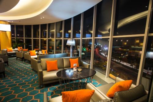a hotel lobby with couches and a table with orange pillows at Hotel Ciputra Cibubur managed by Swiss-Belhotel International in Cibubur