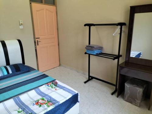 ein Schlafzimmer mit einem Bett, einem Spiegel und einer Kommode in der Unterkunft EZ Homestay Lundang Kota Bharu in Kota Bharu