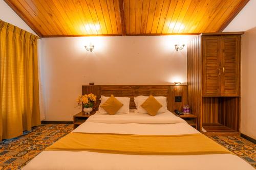 a bedroom with a large bed and wooden ceilings at Red Button Resort in Mahabaleshwar