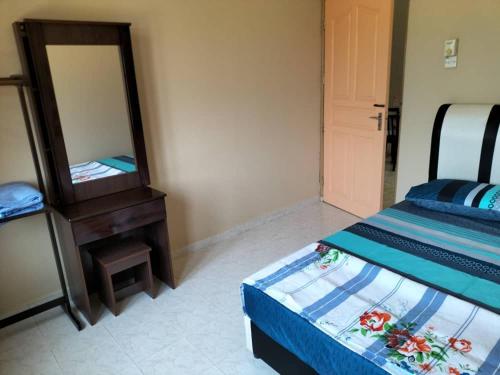 Schlafzimmer mit einem Bett, einer Kommode und einem Spiegel in der Unterkunft EZ Homestay Lundang Kota Bharu in Kota Bharu