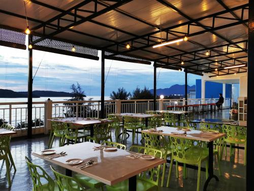 a restaurant with tables and chairs with a view of the water at Langkapuri Resort Langkawi in Pantai Cenang