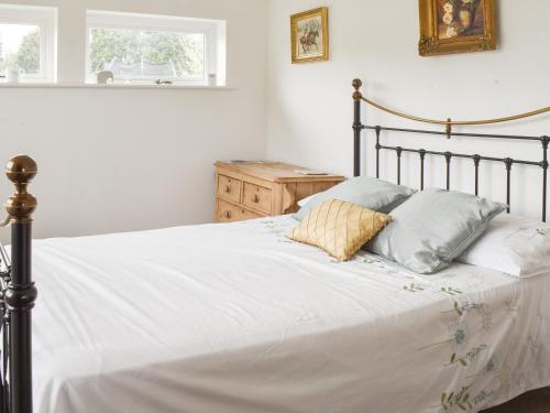 um quarto com uma cama com lençóis brancos e almofadas em The Lodge - Oakwood Park Polo Club em Maresfield