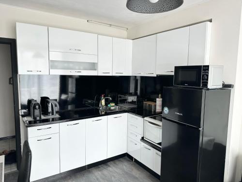 a kitchen with white cabinets and a black refrigerator at Budget Luxury Apartment - Absolutely New Building! in Ruse