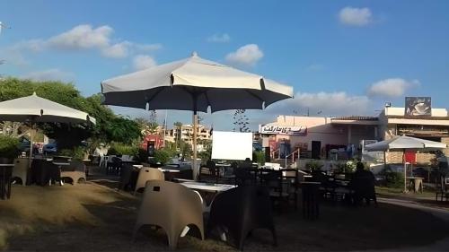 a group of tables and chairs with umbrellas at Villa with Roof, Private Garden and Backyard in North Coast - Families Only فيلا مستقلة الساحل الشمالي - عائلات فقط in Dawwār Abū Maḩrūs