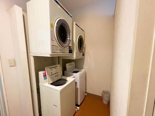 a laundry room with two microwaves and a washer and dryer at Hotel Pearl City Tendo in Tendo