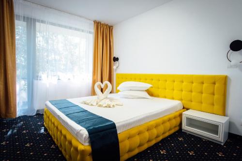 a bed with a yellow headboard in a room at Hotel & MedSpa Siret in Mamaia