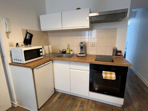une petite cuisine avec un micro-ondes et un évier dans l'établissement Grand studio rdc au calme, centre ville prox Cathédrale, à Orléans