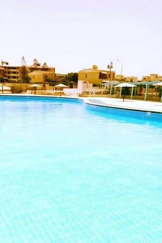 a large pool of blue water with buildings in the background at Villa with Roof, Private Garden and Backyard in North Coast - Families Only فيلا مستقلة الساحل الشمالي - عائلات فقط in Dawwār Abū Maḩrūs