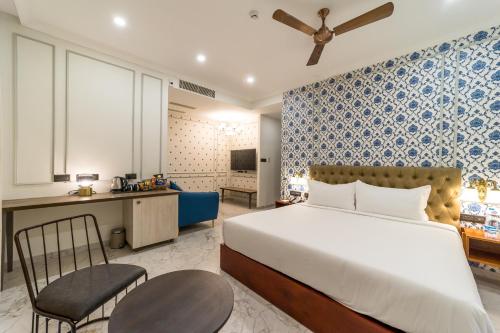 a bedroom with a bed and a desk and a chair at De Fleur Hotel in Puducherry