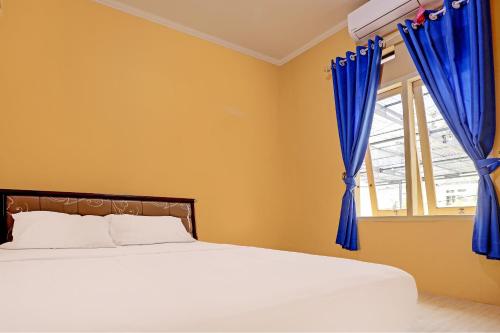 sypialnia z łóżkiem i oknem z niebieskimi zasłonami w obiekcie SPOT ON 92523 Homestay Pasir Padi Permai Syariah w mieście Pangkal Pinang