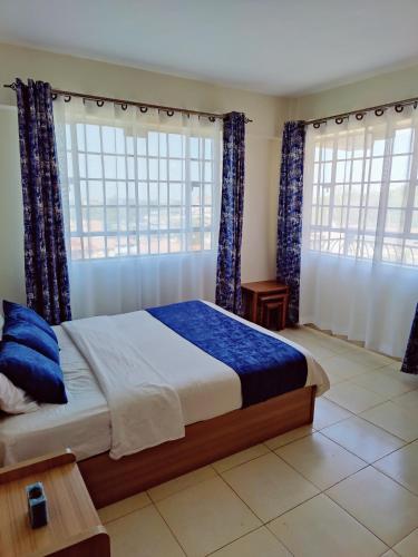 um quarto com uma cama grande e 2 janelas em Modern 1-bdrm Apartment 15min to CBD. 20min to UN em Nairobi