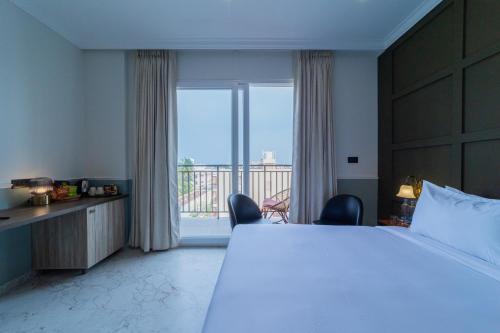 a bedroom with a large bed and a large window at De Fleur Hotel in Puducherry