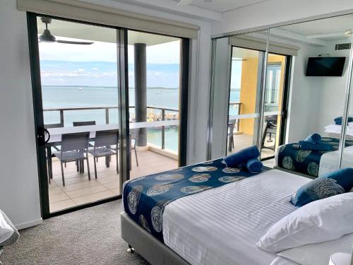 a bedroom with a bed and a balcony with the ocean at Absolute Waterfront - Tropical Oasis Over The Water in Darwin