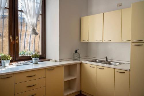 a kitchen with yellow cabinets and a sink and a window at Spacious apartment in strategic location - Green in Trento