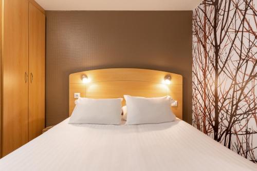 a bedroom with a large bed with white pillows at Sure Hotel by Best Western Plaisir in Plaisir