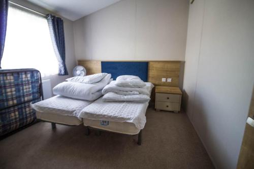 a bedroom with two beds with white sheets and a window at Beautiful 4 Berth Lodge With Decking At Manor Park In Hunstanton Ref 23038c in Hunstanton