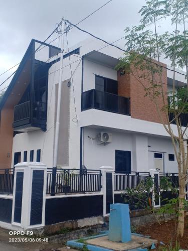 um edifício branco com uma varanda e uma árvore em Villa Aruki Bukittinggi em Bukittinggi
