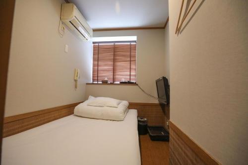 Habitación pequeña con cama y ventana en プチホテル　コスモス, en Tokio