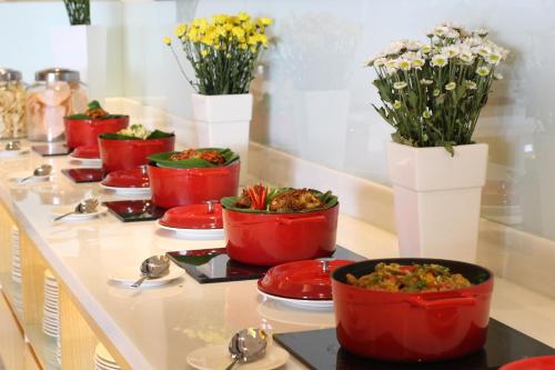 a buffet with red bowls of food and flowers at Hotel Ciputra Cibubur managed by Swiss-Belhotel International in Cibubur