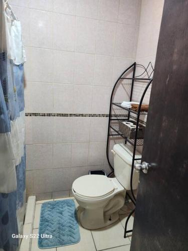 a bathroom with a toilet and a blue rug at Guest house 2 mins from da beach in Puerto Peñasco