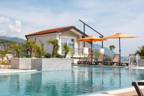 a house with a swimming pool with chairs and umbrellas at Hotel Reset in Budva