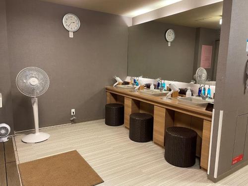 a bathroom with sinks and a mirror with a fan at Dormy Inn Tsu in Tsu