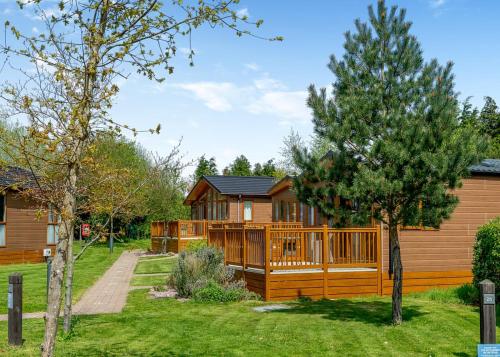 a log cabin with a deck and a yard at Canterbury Reach Lodge Retreat in Kent
