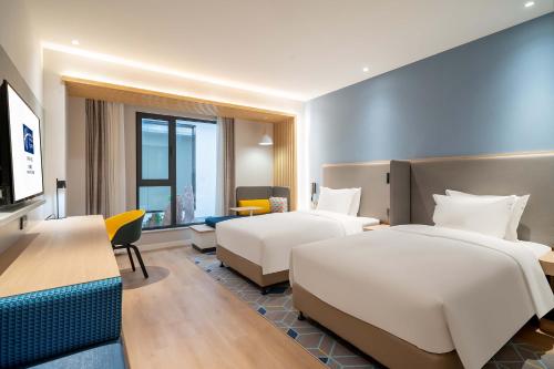 済南市にあるHoliday Inn Express Jinan Airport Zone, an IHG Hotelのベッド2台とデスクが備わるホテルルームです。