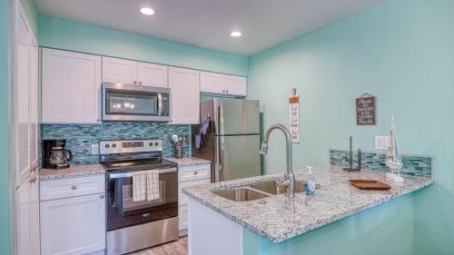 Una cocina con gabinetes blancos y un refrigerador de acero inoxidable. en The Salty Aloha, en Rockport